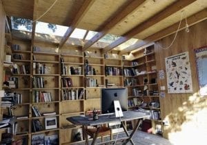 Reading Man Cave shed: Folding table with iMac, walls filled floor to ceiling with book shelves.