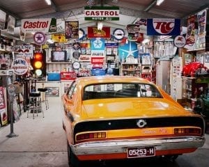 Auto enthusiast shed: Yellow car in garage shed. Walls are covered in auto-themed signs and wall decorations.
