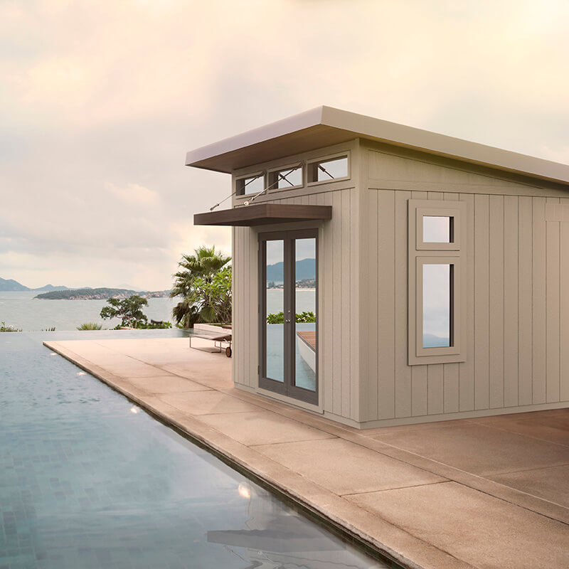 Studio style shed with tan exterior next to pool.