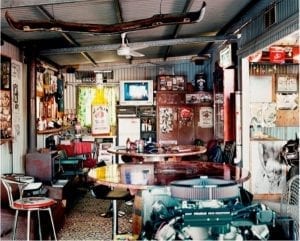 Man Cave shed: Two round glass tables, light-up beer sign, wall art, and other eclectic furniture and decor.